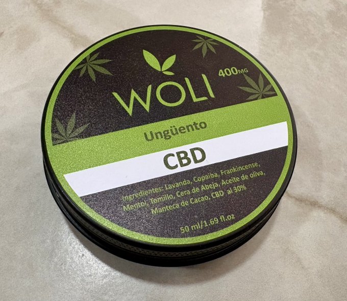 A container of WOLI CBD Unguento (ointment), 400MG, 50 ml/1.69 fl.oz., featuring ingredients like lavender, copaiba, frankincense, and olive oil.