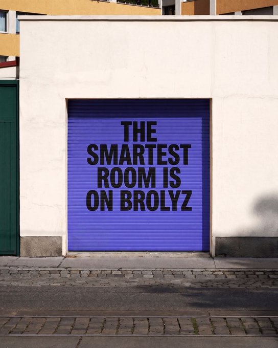 A bright purple garage door with black text reading 'THE SMARTEST ROOM IS ON BROLYZ' on a white building facade.