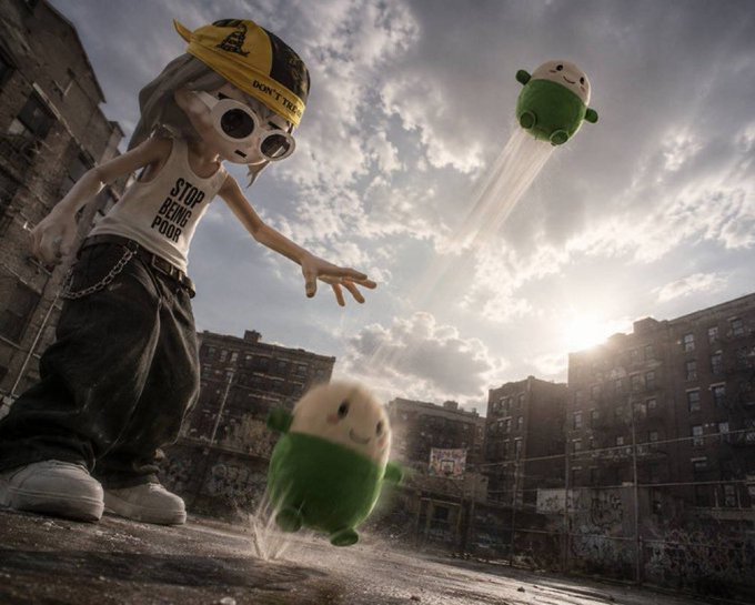 A stylized scene featuring a character in a 'STOP BEING POOR' tank top tossing green, smiling blob-like creatures across an urban landscape at sunset.