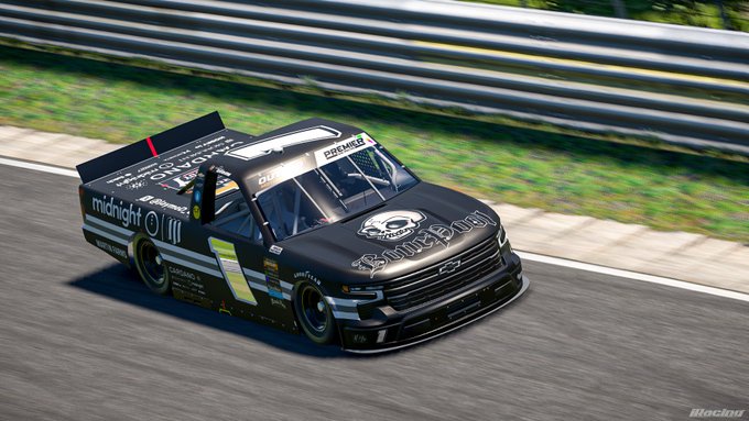 A black racing truck sponsored by 'midnight' and 'shutters' speeds around a track, displaying the number '01' on its door and 'DREYER & REINBOLD RACING' on its rear panel.