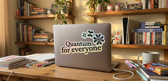 The image shows a laptop computer sitting on top of a wooden desk surrounded by various books and papers. The laptop has a sticker that says "Quantum for everyone" written on it. In front of the laptop, there are some books and papers scattered around, suggesting that someone might be working or studying.