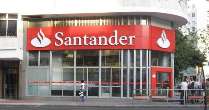 A Santander bank branch displays the company's signature red signage and logo, representing the Spanish banking giant that recently disclosed holding approximately $4.3 million worth of BlackRock's IBIT Spot Bitcoin ETF shares. The storefront image visually anchors the news about Santander's entry into Bitcoin ETF investments, highlighting how traditional major banks are beginning to embrace cryptocurrency exposure.