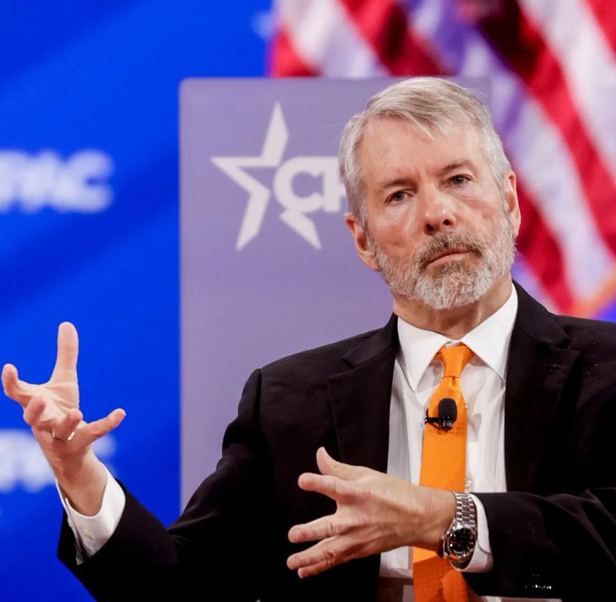 "The world runs on credit - soon it'll be digital credit." The image features a man wearing an orange tie, giving him a professional appearance as he speaks at a podium. He has his hands outstretched, emphasizing his point during the presentation. The background includes a flag and text that reads "CPAC".