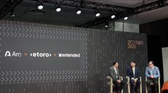 Three men are seated on a stage during a panel discussion at an event, with a backdrop displaying logos for 'Arc', 'eToro', and 'Wonderland', along with the text 'TGE COLLECTIVE'.