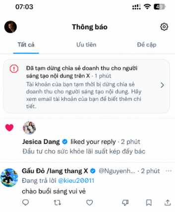 A smartphone screenshot of a Vietnamese notification screen ("Thông báo") showing the time 07:03 with notifications about revenue sharing for content creators on X, a reply liked by "Jesica Dang", and a post by "Gấu Đỏ /lang thang X" saying "chào buổi sáng vui vẻ" (happy morning).