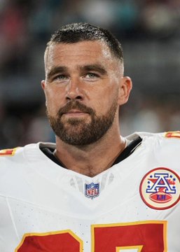 A close-up of a Kansas City Chiefs NFL player in a white jersey, looking serious on the field.