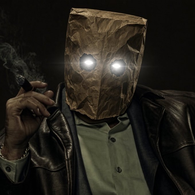 A figure with glowing eyes peering through a crumpled brown paper bag mask smokes a cigar while wearing a leather jacket over a green shirt, evoking the dark, mysterious "kingmaker" persona the poster references in their confident trading narrative about an under-the-radar investment opportunity.