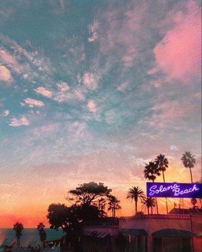 A scenic sunset photograph featuring a pink and blue sky with scattered clouds over a beachfront, with palm trees and a neon 'Solana Beach' sign visible in the distance.