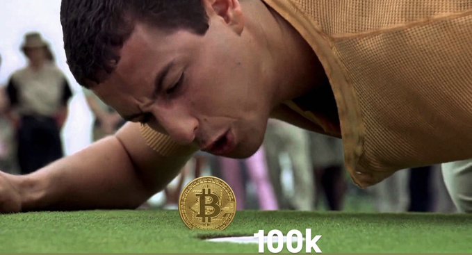 A humorous edited image showing a man face-down on grass about to kiss a physical Bitcoin coin with '100k' written in the corner.