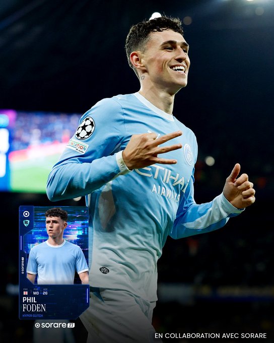Phil Foden celebrates in a light-blue Manchester City kit, pointing toward the camera and giving a thumbs-up. A Sorare card graphic at lower left reads “PHIL FODEN,” “MID 28,” and “sorare,” matching the post about his hat-trick, 100/100 rating, and man-of-the-match award against AEK.