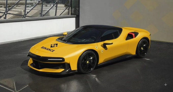 A yellow sports car featuring 'BINANCE' branding and logos on its hood is parked indoors on a dark surface.