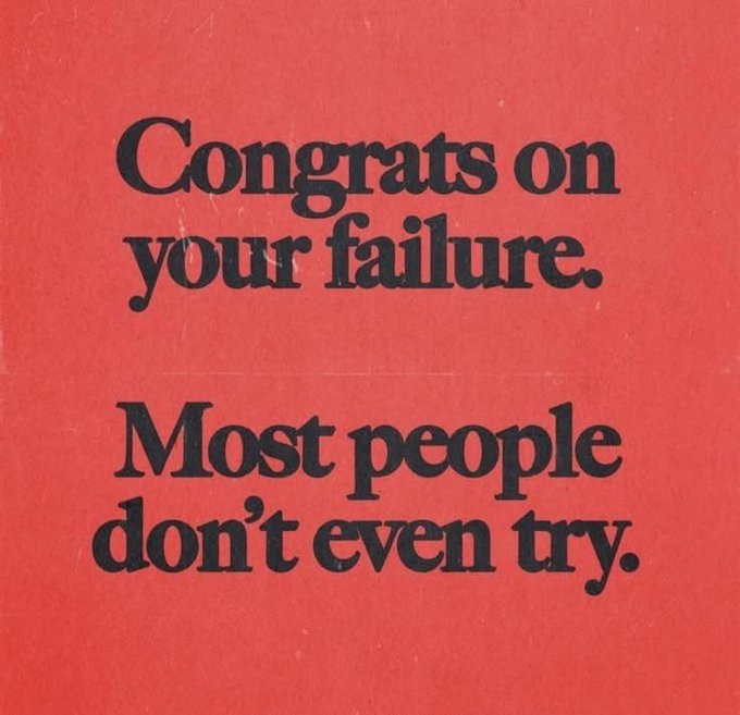 A red sign with bold black text reads, 'Congrats on your failure. Most people don't even try.'