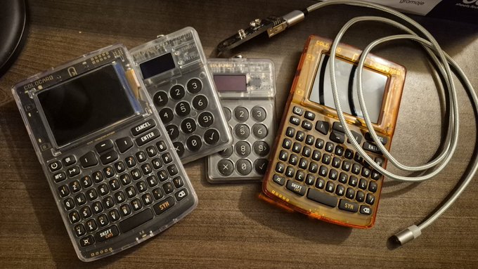 Several Coldcard hardware wallets with "COLDCARD" branding and QWERTY keyboard layouts rest on a wooden surface alongside a USB cable and what appears to be a security device, in the wake of a reported security breach where user funds were lost.