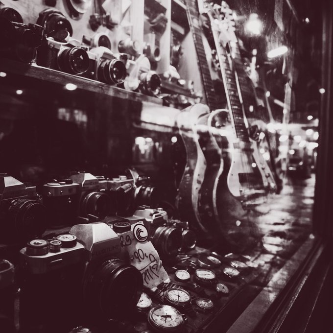 A black-and-white photograph shows a display case filled with vintage cameras, watches, and electric guitars lined along a storefront window, with reflections of street lights visible on the glass.

The image evokes a sense of enduring craftsmanship and quiet dedication—artifacts like classic cameras and timepieces have stood the test of time through constant use and care, mirroring how the BitTorrent ecosystem thrives through builders and node operators who keep showing up and maintaining the network long after the spotlight fades.