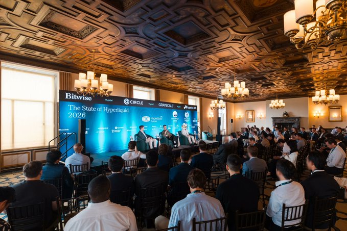 A panel discusses "The State of Hyperliquid 2026" at the first-ever Hyperliquid Summit in NYC, attended by financial professionals. The image visually captures the summit event described in the accompanying post.