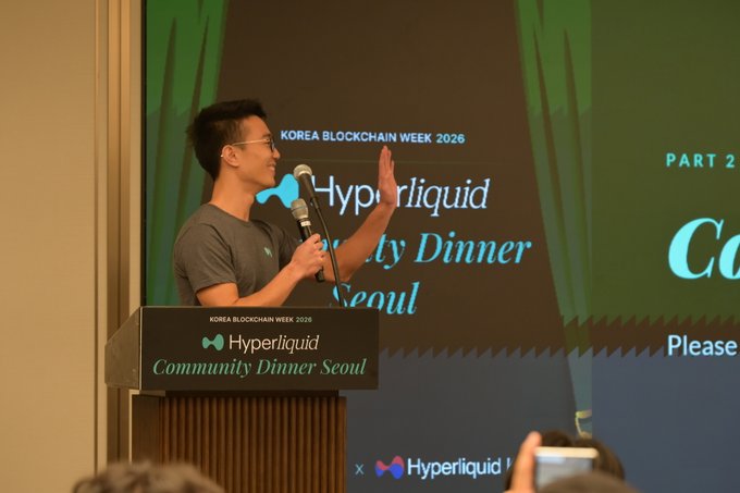 A speaker addresses the audience at the Hyperliquid Community Dinner Seoul during Korea Blockchain Week 2026, gesturing while holding a microphone beside a podium displaying the event's logo. The backdrop confirms the gathering, illustrating the post's celebration of familiar and new faces who came together in Seoul for Hyperliquid.