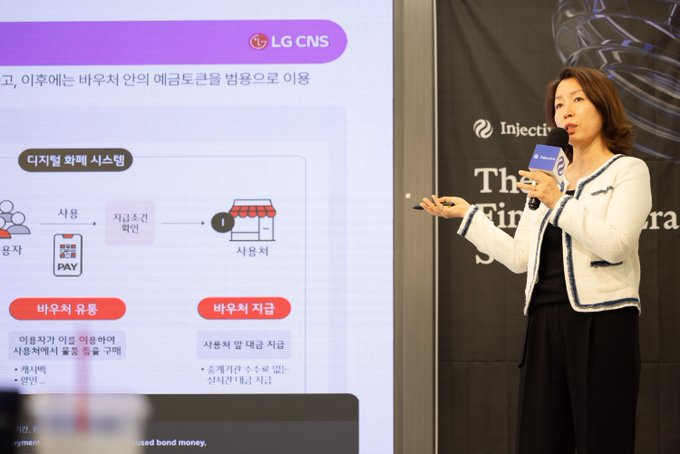 A woman in a white blazer presents at Injective's KBW event in Seoul, with the LG CNS logo and a slide explaining digital asset services like digital bond systems displayed beside her, highlighting LG CNS's role as one of the featured industry speakers.