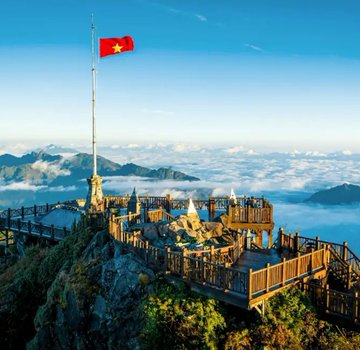 A Vietnamese flag flies atop a scenic mountain overlook above a sea of clouds, evoking the nation's identity as it prepares to implement new crypto regulations.
