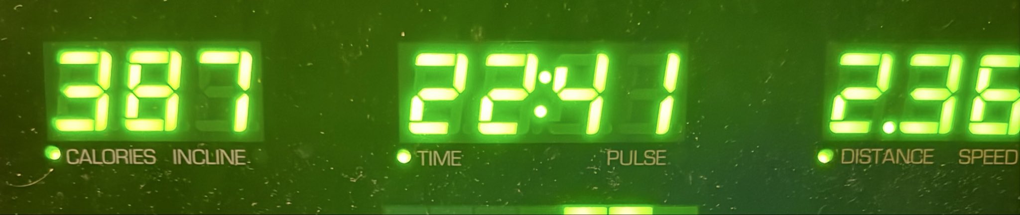 A close-up of a green LED display showing '337' for calories/incline, '24:41' for time/pulse, and '2.35' for distance/speed.
