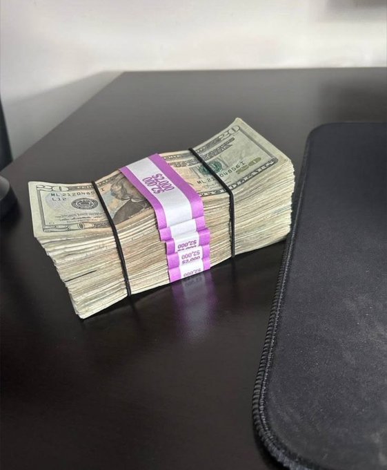 A thick stack of $20 bills banded with purple "$2,000" straps sits on a dark desk, visually representing the "make money" theme of the post. The bands are labeled "TWENTIES" and "ML2104041," reinforcing the celebratory tone of the caption.