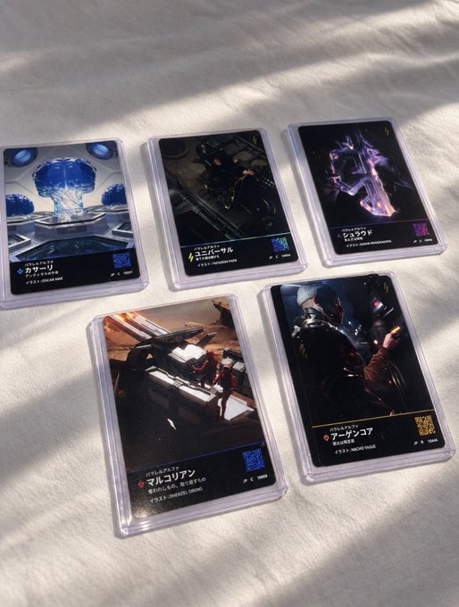 Five collectible trading cards from the Godzilla card game laid out on a white surface, featuring characters like Mothra, Manda, and various other kaiju.
