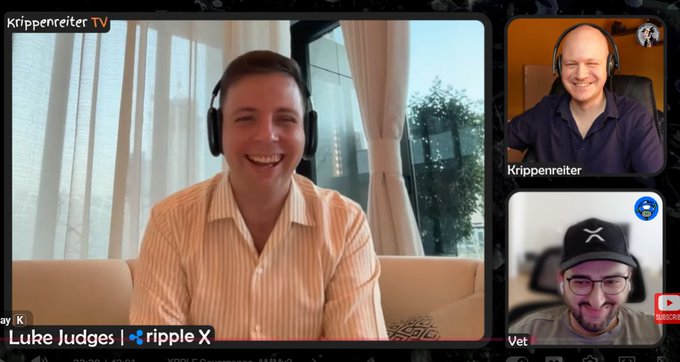 The image shows three men sitting down together, each wearing headphones and smiling at the camera. They are all looking at a computer screen that displays their names along with some text related to Ripple blockchain technology. The man in the center of the frame is wearing an orange shirt and has his arms crossed over his chest. The other two men have their arms resting on their knees, also wearing headphones.