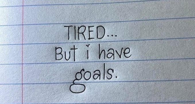 Handwritten note on lined paper reads "TIRED... But i have goals." — the image reflects the perseverance mindset behind the post's call to drop SOL wallets and engage despite fatigue.