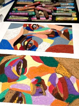 Two colorful abstract portrait paintings created with oil pastels, with boxes of pastels visible at the top of the image.