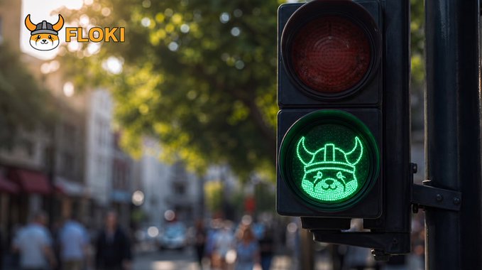 A green traffic light glows in an urban street setting, with a Viking helmet emblem illuminated in the green signal and the "FLOKI" logo featuring a Shiba Inu mascot displayed in the top corner, reinforcing the post's message to "keep building" and signaling a bullish go-ahead for the FLOKI community.