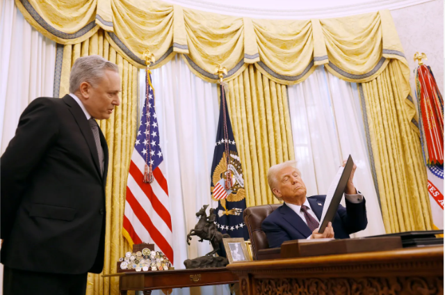 Tổng thống Donald Trump ngồi sau bàn làm việc trong Phòng Bầu dục, cầm một tài liệu khi một quan chức đứng cạnh. Hình ảnh minh họa thông điệp chính quyền Mỹ ủng hộ tiền điện tử, sau khi Bitcoin vượt $70,000 và ETH tăng gần 20%.