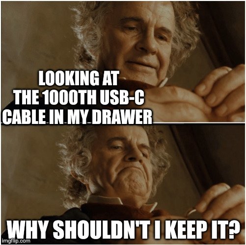 The image is a two-panel meme featuring an older man examining a small object. In the top panel, text reads "LOOKING AT THE 1000TH USB-C CABLE IN MY DRAWER," while the bottom panel shows him making a contemplative face with the text "WHY SHOULDN'T I KEEP IT?" This humorously illustrates the relatable struggle of accumulating countless spare cables and being unable to throw them away, fitting the theme of feeling tethered to USB-C cables.