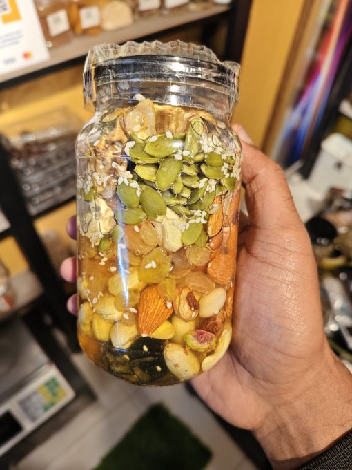 The image shows a person holding a jar filled with nuts and seeds, likely almonds or cashews, as they are being held up against a gray background. The text above the image reads "Good afternoon CT champ," which could be an autocorrect error or part of a caption that was added to the image by someone else.
