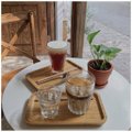 A wooden tray holds a small candle, a cup of coffee, and a potted plant on a marble table, with burnt wooden planks visible in the background. The image appears unrelated to the post's text, which jokes about someone's dangerous mischief and mentions handling fire, with tags @CNPYNetwork and @BeldexCoin.