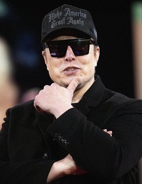 A man wearing sunglasses and a black cap with 'Make America Great Again' text, dressed in a black coat with his hand near his chin.