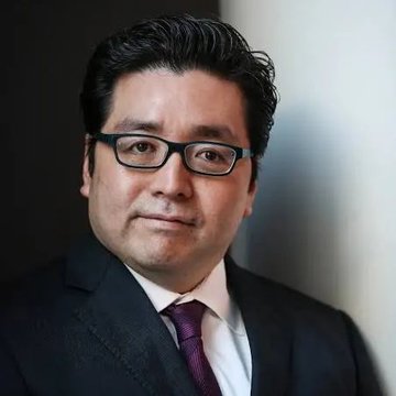A professional headshot of Tom Lee in a dark suit, white shirt, and maroon tie with glasses, presented alongside news that BitMine, associated with him, purchased 27,084 ETH worth approximately $43 million.