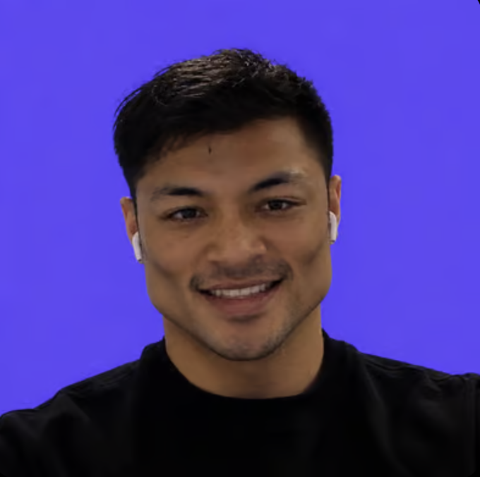 A smiling man wearing white earbuds and a black shirt is pictured against a solid purple background, appearing in what looks like a video call screenshot. The image seems to capture a celebratory or announcement moment, fitting with the post's excitement about reaching 10M $MON volume on OpenSea.