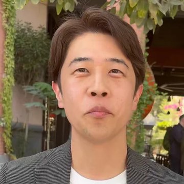 A man with short dark hair, wearing a checkered blazer over a white shirt, stands outdoors with greenery in the background. The image accompanies a post about JASMY CFO Hara predicting a massive price surge to $17, implying a $107 billion market cap, though no specific text or numbers are visible in the photo itself.