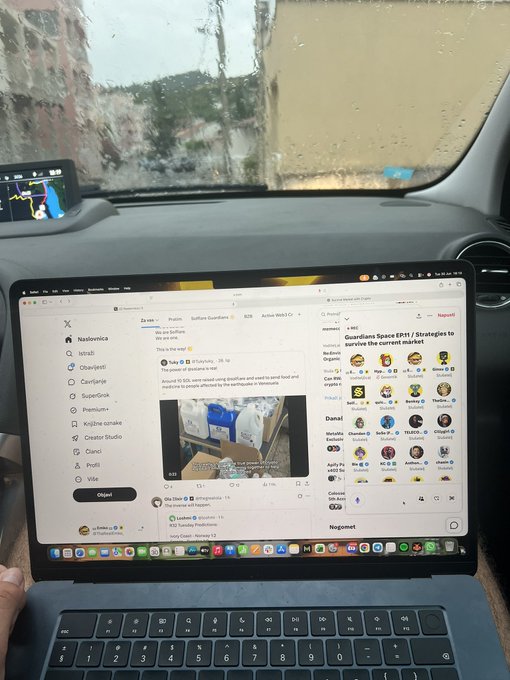 A view from inside a car during rain, with a laptop on the passenger seat displaying the X (formerly Twitter) social media platform.