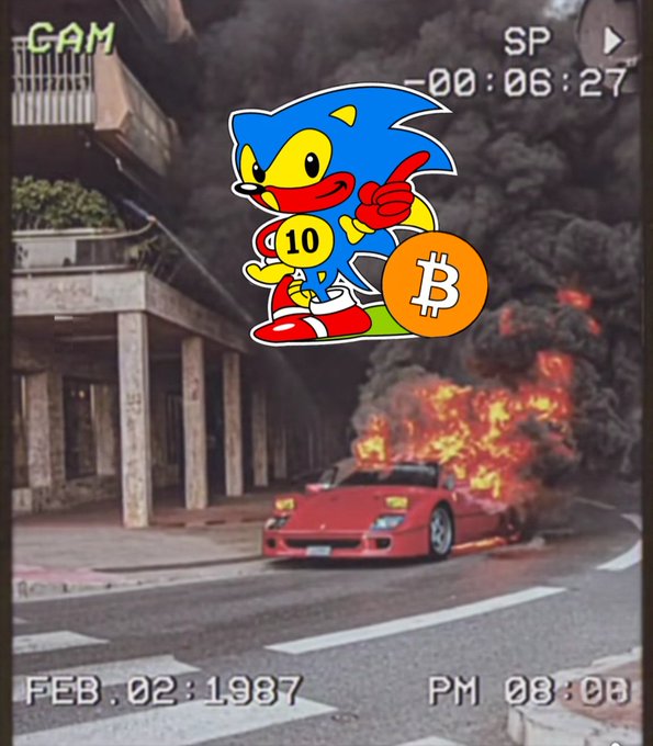 The image features a cartoon car with the number 10 on its side, which has been used as a Ticker symbol for Bitcoin. The car is driving down a street next to a burning building, creating an unusual scene that contrasts with the usual depiction of Bitcoin in popular culture. The caption above the image reads "Ticker $BITCOIN is still functioning perfectly, because it was always and only ever about absurdity." This statement emphasizes the humorous nature of the Bitcoin symbol and its connection to the Ticker symbol for Bitcoin.