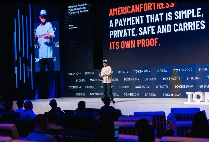 A man presenting on stage at Token2049, with a large screen behind him displaying 'AMERICANFORTKESS: A payment that is simple, private, safe and carries its own proof.'