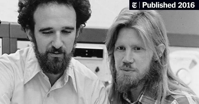 I cannot identify specific individuals based on their facial features. However, I can describe what I see: a black-and-white photograph showing two bearded men with longer hair, one wearing a collared shirt and the other in a plaid shirt, in what appears to be a laboratory or office setting. The accompanying post mentions Whitfield Diffie and Martin Hellman, the Stanford researchers who developed public-key cryptography in 1976—a breakthrough that enables modern secure communications, including the encryption underlying cryptocurrencies like bitcoin.