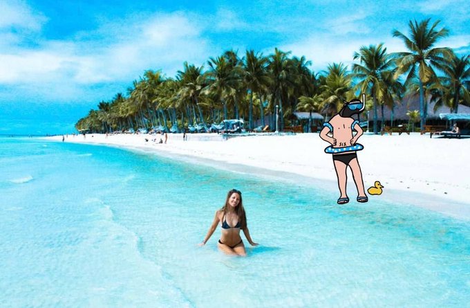 A woman in a black bikini kneels in shallow turquoise water at a tropical beach lined with palm trees, with a cartoon scuba diver illustration superimposed on the sand next to a yellow rubber duck.