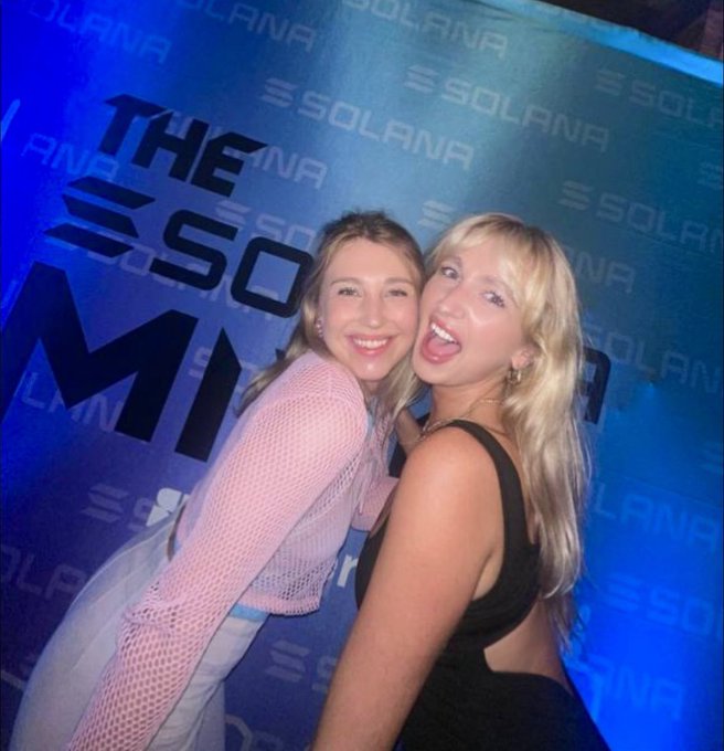 Two women pose together at what appears to be a Solana-sponsored event, smiling for the camera in front of a blue backdrop featuring repeated "SOLANA" logos and "THE SOLANA MI..." text. The festive, excited vibe of the photo aligns with the post's anticipation for the upcoming Solana Breakpoint conference following Token2049.
