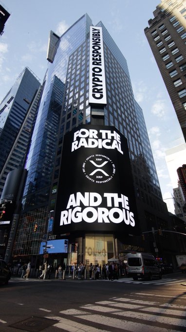 A tall building in a city displays a large vertical banner reading 'CRYPTO RESPONSIBLY' and 'FOR THE RADICAL AND THE RIGOROUS' along with a circular X logo.