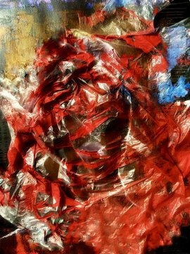 An abstract painting dominated by thick, textured strokes of red and orange paint with hints of blue and yellow in the background.