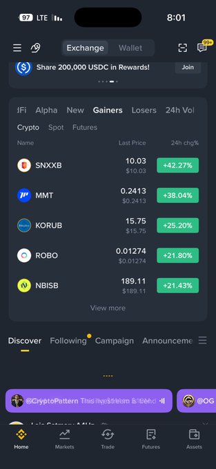 The image shows a cryptocurrency exchange app interface displaying the "Gainers" tab under Crypto markets, featuring top performers like SNXXB (+42.27%), MMT (+38.04%), KORUB (+25.20%), ROBO (+21.80%), and NBISB (+21.43%). The accompanying post in Arabic translates to "Binance flipped US stocks... do you like the situation?" suggesting the user is commenting on how crypto assets are now outperforming traditional American stocks, as evidenced by the strong 24-hour gains shown on the screen.