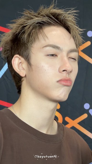 A close-up portrait of a young man winking at the camera with a pouty expression, wearing a brown t-shirt, with a small watermark reading 'keyutuan' at the bottom.