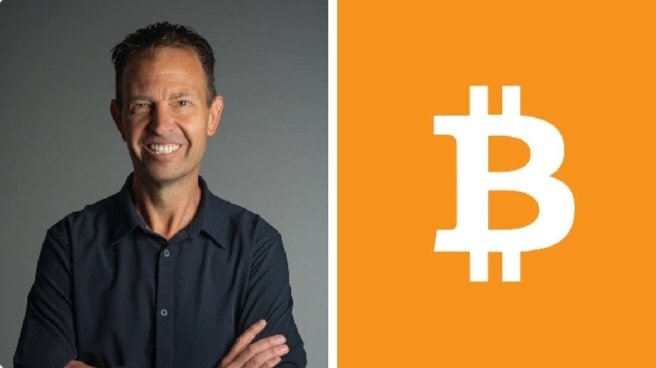 A smiling man in a dark blue shirt stands with arms crossed next to an orange panel displaying the white Bitcoin (₿) logo, visually complementing the post's theme of Bitcoin as a new monetary benchmark rather than a dollar-denominated trade.