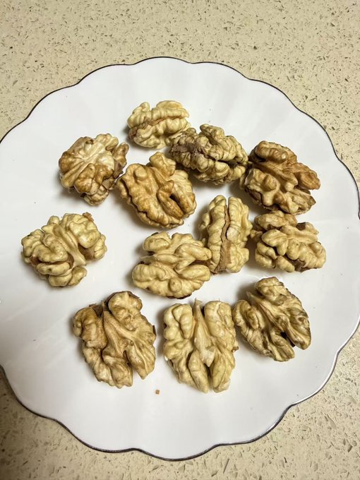 Shelled walnut kernels arranged on a white scalloped plate, freshly harvested and ready to eat.

The image of fresh walnuts on a plate visually supports the post's theme about stocking up on Miyi's new walnut harvest and indulging in them for nourishment.