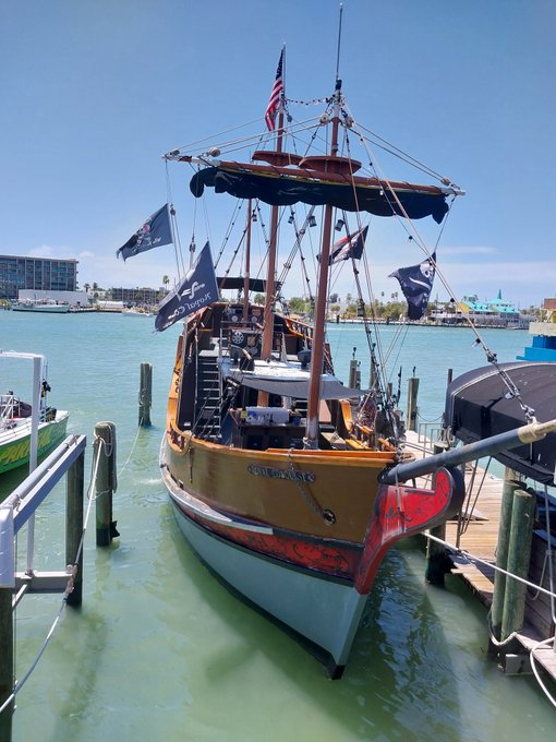 A pirate-themed tourist boat named 'Lost Boys' docked at a marina, flying an American flag and pirate flags, likely at John's Pass in Florida.